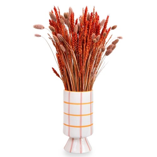 A white vase with dried grains in shades of red